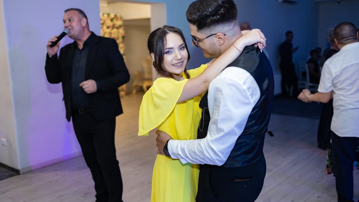 A joyful couple dancing at an indoor wedding with live entertainment.