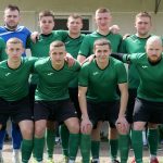 A group of amateur soccer players posing together in sportswear outdoors.