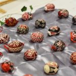A collection of intricately designed Hungarian Easter eggs displayed on satin fabric.